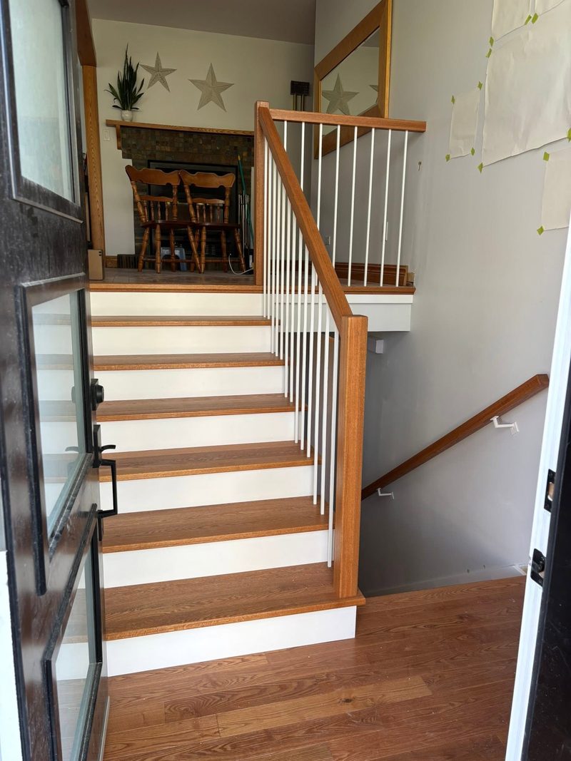 Escalier d'entrée en bois avec contremarches blanches et garde-corps à barreaux