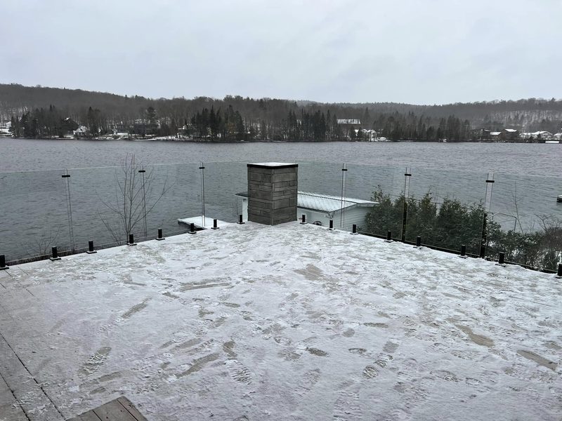 Terrasse sur le toit avec garde-corps de verre face à un lac