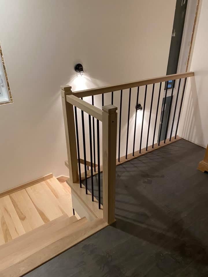 Palier d'escalier en bois clair avec garde-corps à barreaux noirs